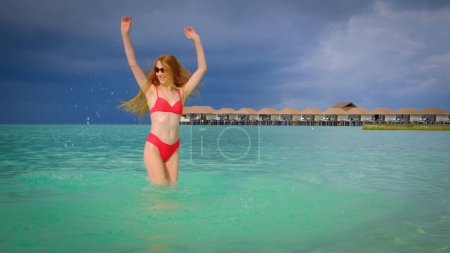 Photo for Woman in a bikini is happy on Maldives. Blue turquoise ocean on the background. Girl enjoys her tropical holidays. Summer travel vacation concept. - Royalty Free Image