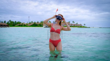 Foto de La mujer en bikini rojo está buceando feliz en Maldivas. Océano azul turquesa en el fondo. Chica disfruta de sus vacaciones tropicales. Concepto de vacaciones de verano. - Imagen libre de derechos
