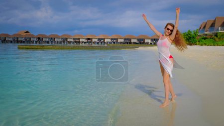 Téléchargez les photos : Une femme en bikini est heureuse. Femelle est heureuse aux Maldives. Océan bleu turquoise sur le fond. Fille profite de ses vacances tropicales. Voyage d'été concept de vacances. - en image libre de droit