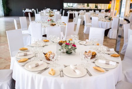Foto de Foto de recepción de boda. Gafas y flores en las mesas. Boda restaurante decoración interior blanca, sin personas. - Imagen libre de derechos