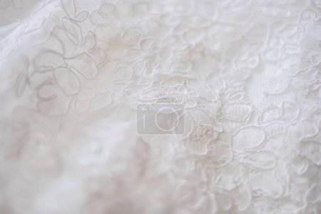 Gros plan d'une dentelle sur une robe de mariée. Photo de haute qualité. Vue d'un motif de fleurs blanches sur robe nuptiale classique blanche.