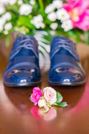 Téléchargez les photos : Close up of small bouquet with flowers laying near man wedding clothes. Close-up of a grooms shoes. Blue beautiful wedding accessory. - en image libre de droit