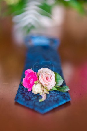 Foto de Close up of small bouquet with flowers laying on a man wedding clothes. Close-up of a grooms tie. Blue beautiful wedding accessory. - Imagen libre de derechos