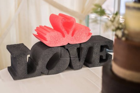 Foto de Styrofoam letters forming the word love and swans. Wedding decoration at a reception. Romantic beautiful decor for a nuptial event. - Imagen libre de derechos