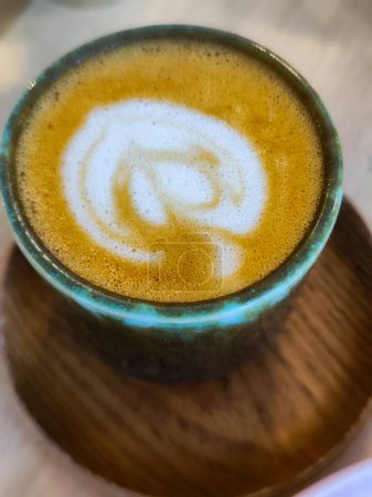 Foto de Una taza de café en la mesa. Cerrar taza de café blanco con forma de corazón de latte art foam. Foto vertical. - Imagen libre de derechos