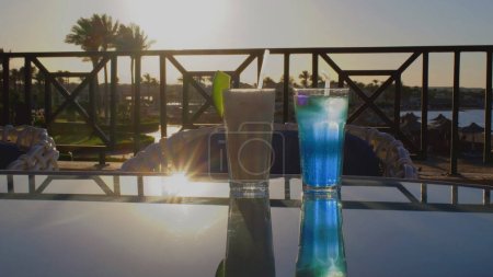 Téléchargez les photos : Deux cocktails au bord de mer au coucher du soleil. Deux cocktails se tiennent sur une table en verre. Belle réflexion sur un verre. - en image libre de droit