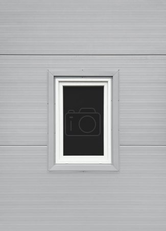 Téléchargez les photos : Fenêtre rectangulaire dans un cadre blanc sur la façade d'un bâtiment industriel gris. Texture, maquette - en image libre de droit