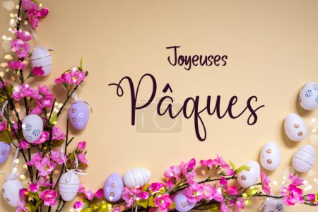 Französischer Text Joyeuses Paques bedeutet frohe Ostern auf beigem Hintergrund. Rosa und lila, glänzende und leuchtende Frühlingsblumen mit Ostereierdekoration.