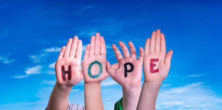 Children Hands Building Colorful English Word Hope. Blue Sky As Background.