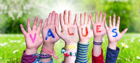 Téléchargez les photos : Children Hands Building Colorful English Word Values. Été, prairie d'herbe verte ensoleillée comme fond - en image libre de droit