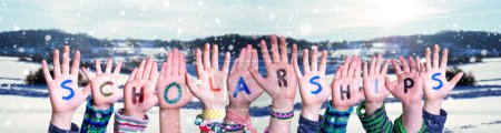Photo for Children Hands Building Colorful English Word Scholarships. White Winter Background With Snowflakes And Snowy Landscape. - Royalty Free Image