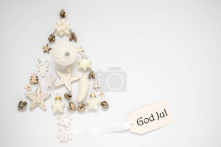 Téléchargez les photos : Fond plus blanc avec un arbre de Noël sur la décoration de Noël, avec une étiquette avec texte suédois Dieu juil, ce qui signifie Joyeux Noël en anglais - en image libre de droit