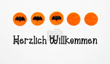 Foto de Fondo blanco de Halloween con puntos naranjas y murciélagos negros y texto alemán Herzlich Willkommen, lo que significa bienvenido en inglés - Imagen libre de derechos