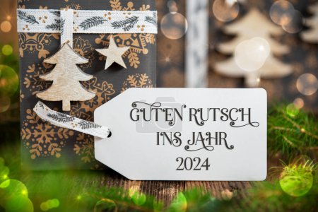 Foto de Texto alemán Guten Rutsch Ins Jahr 2024, significa feliz año nuevo 2024 en inglés, en una etiqueta blanca con regalos de Navidad, regalos de invierno, fondo natural y respetuoso del medio ambiente - Imagen libre de derechos