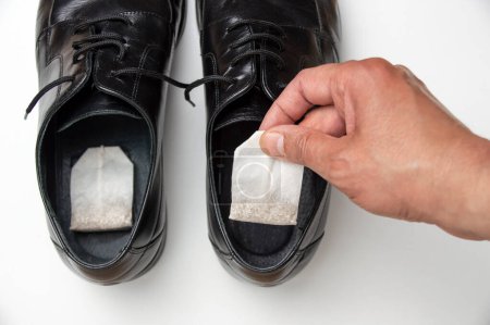 Photo for Close up of hand puts the tea bag in shoes. concept of removing unpleasant odors - Royalty Free Image