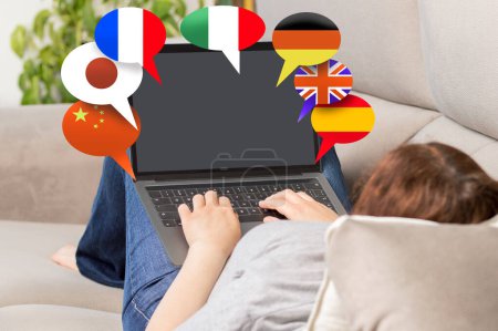 Foto de Rearview shot of a woman using a laptop with bubble speech flags at home.Learning languages online, translate concept. - Imagen libre de derechos