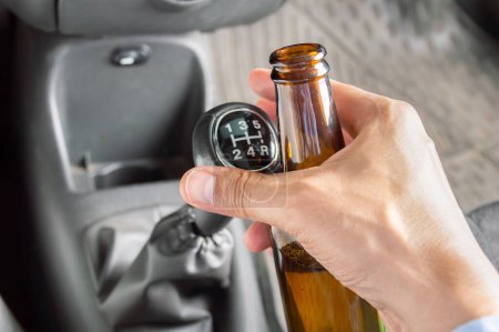 Téléchargez les photos : Close-up of hand driving car and drinking alcohol dangerously - en image libre de droit