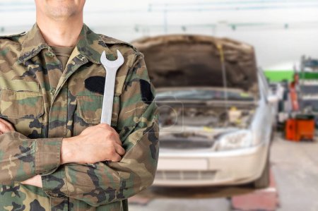 Téléchargez les photos : Hand of a military car mechanic with wrench. Car repair garage. - en image libre de droit