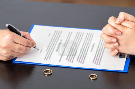 Foto de Agreement prepared by lawyer signing decree of divorce or dissolution and cancellation of marriage, husband and wife during divorce process at office - Imagen libre de derechos