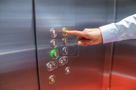 Téléchargez les photos : Closeup shot of an unrecognisable man pushing a button in an elevator - en image libre de droit