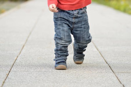 Téléchargez les photos : Image recadrée des jambes d'un bébé marchant dans la rue - en image libre de droit