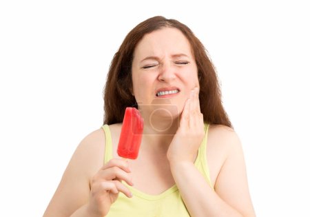 Téléchargez les photos : Portrait of a woman with hypersensitivity biting ancold ice cream isolated on white - en image libre de droit