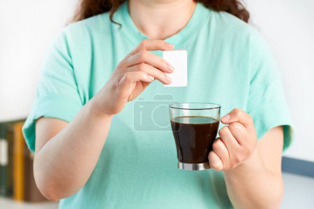 Foto de Cortado tiro de una mujer manos lanzando sacarina en una taza de café en casa - Imagen libre de derechos