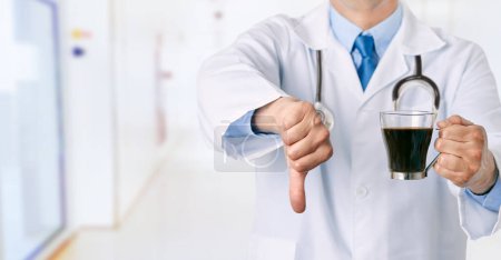 Foto de Vista frontal de cerca de las manos de un médico masculino sosteniendo una taza de café con el pulgar hacia abajo en el hospital y espacio de copia - Imagen libre de derechos