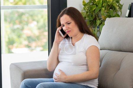 Photo for Shot of a painful pregnant woman calling doctor at home - Royalty Free Image