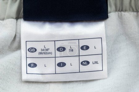 Foto de Etiqueta de etiqueta de ropa Size L, con muchas escalas diferentes en tela blanca, aislada en blanco, macro primer plano detallado.Reino Unido, España, Francia, Países Bajos, Italia y Alemania - Imagen libre de derechos