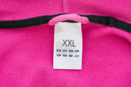 Foto de Etiqueta de etiqueta de ropa de tamaño XXL, tela blanca, aislada en rosa, macro detallado primer plano - Imagen libre de derechos