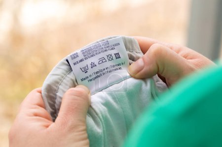 Photo for Close-up of person reading the clothing label showing washing instructions at home - Royalty Free Image