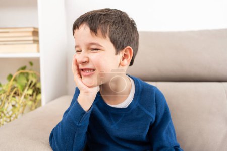Gestresstes Kind klagt über Zahnschmerzen, wenn es auf dem Sofa im Wohnzimmer sitzt