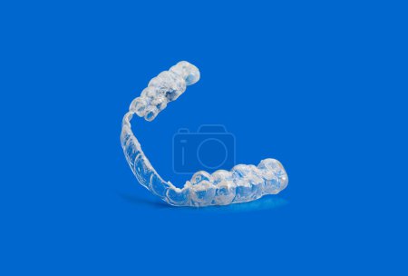 Abgenutzte und kaputte unsichtbare kieferorthopädische Zahnspangen auf blauem Hintergrund mit Kopierraum. Ausrichtung zum Richten der Zähne
