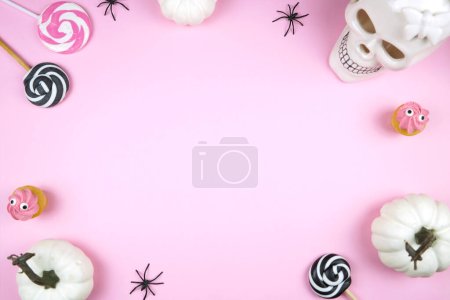 Photo for Pink Halloween framed border background backdrop. Trick or treat party styled with white skull, pumpkins, black spiders, and spooky cupcakes. Negative copy space. - Royalty Free Image