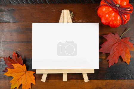 Otoño rústico Cena de Acción de Gracias producto Mockup. Mesa caballete, mesa número 5x7 maqueta de la tarjeta, estilo con hojas de otoño y calabaza sobre fondo de madera oscura.