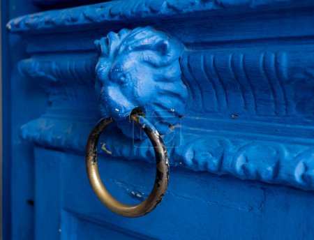 Téléchargez les photos : Blue doorknob in the form of a lion's head with a ring  on a wooden ornament - en image libre de droit