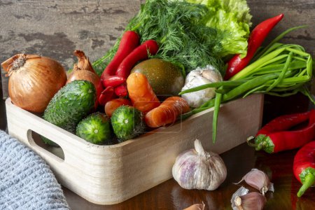Téléchargez les photos : Légumes mûrs, carotte, tomate, ail, laitue aux oignons, piment dans une boîte en bois léger - en image libre de droit