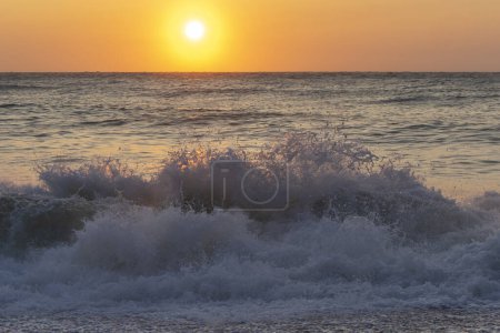 Téléchargez les photos : Onde de mer sur fond de soleil couchant - en image libre de droit