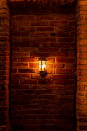 Téléchargez les photos : Lanterne allumée sur un mur de briques rouges - en image libre de droit