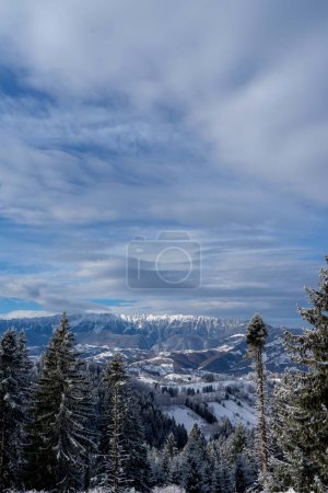 Téléchargez les photos : Chaîne de montagnes enneigée, sur fond de ciel bleu et de nuages, vue de la forêt - en image libre de droit