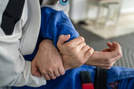 Téléchargez les photos : Deux athlètes dressant le bras de soumission brésilien jiu jitsu americana BJJ dans un uniforme de kimono gi à l'académie - en image libre de droit