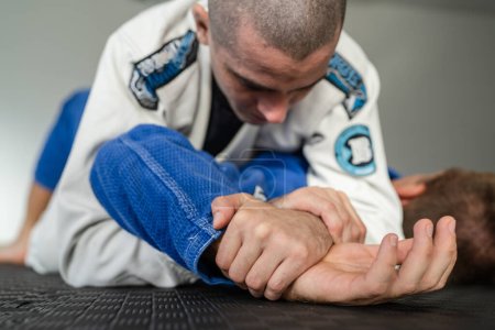 dos atletas entrenamiento brasileño jiu jitsu americana sumisión brazo bloqueo BJJ en un kimono gi uniforme en la academia