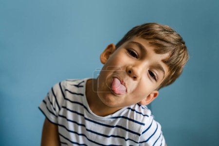 Foto de Un niño caucásico en frente de la pared azul en casa jugando alrededor de retrato interior infancia creciendo concepto - Imagen libre de derechos