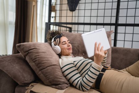 eine Frau erwachsenen kaukasischen weiblichen Millennials mit Kopfhörern für Online-geführte Meditation üben Achtsamkeit Yoga oder wählen Sie Musik auf dem Bett zu Hause echte Menschen Selbstpflege-Konzept kopieren Raum