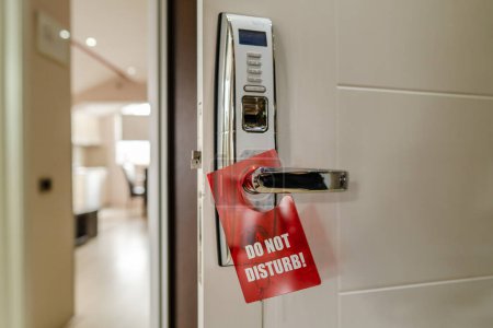 Téléchargez les photos : Close up on the opened door with modern key lock of hotel motel room with Do Not Disturb sigh hanging off the door handle - en image libre de droit