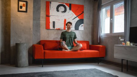 Téléchargez les photos : Un homme adulte caucasien masculin utilisent des écouteurs pour la méditation guidée en ligne pratiquant le yoga pleine conscience avec les yeux fermés à la maison personnes réelles auto-soins concept de manifestation copier l'espace - en image libre de droit