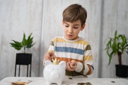 Foto de Portrait of caucasian boy six years old saving money with piggy bank - Imagen libre de derechos