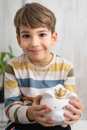 Photo for Portrait of caucasian boy six years old saving money with piggy bank - Royalty Free Image