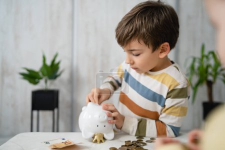 Téléchargez les photos : Small caucasian boy six years old count money from piggy bank savings - en image libre de droit